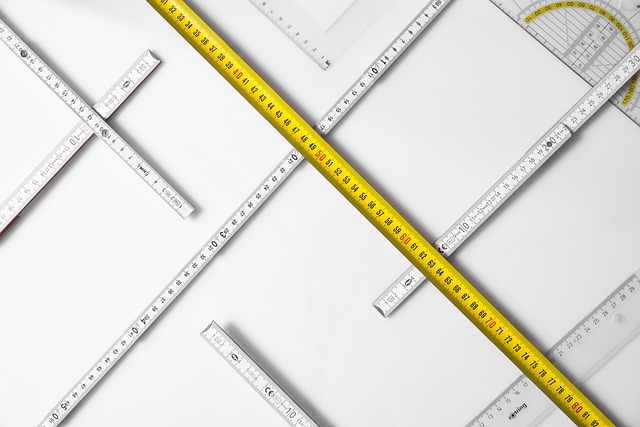 Stoffproben und Werkzeuge wie Maßband, Stecknadeln und Schneiderkreide auf Tisch